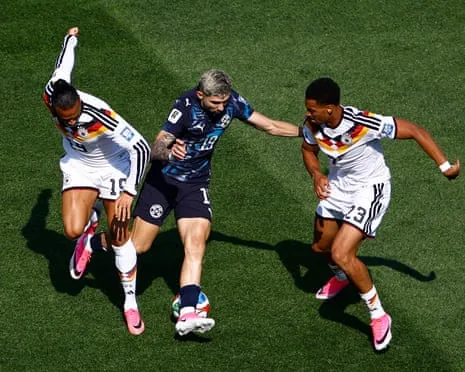 Paraguay's Julio Enciso in action with Germany's Leroy Sane and Felix Nmecha.