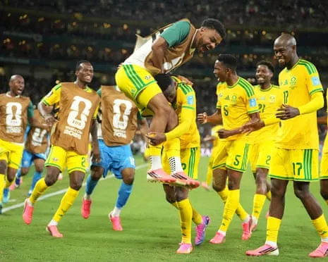 Thapelo Maseko is jumped on by teammates as South Africa celebrate scoring against South Korea